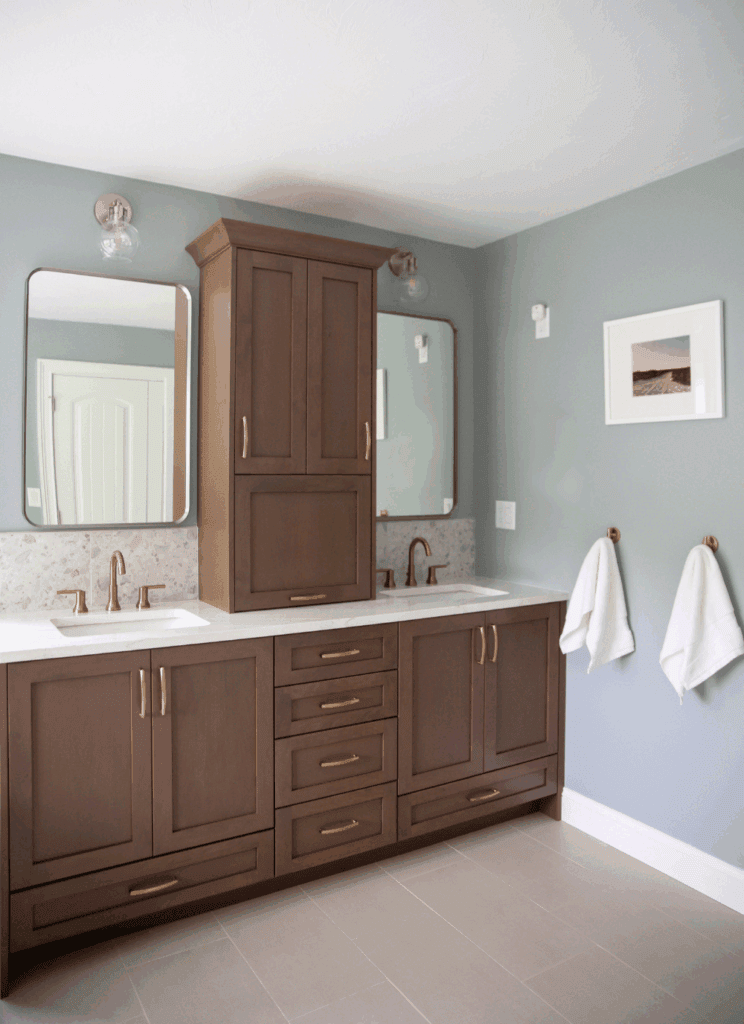 WoodHarbor cherry vanity in Cashmere finish with champagne bronze towel hooks, white quartz countertop, and terrazzo tile backsplash in primary bath by KRB