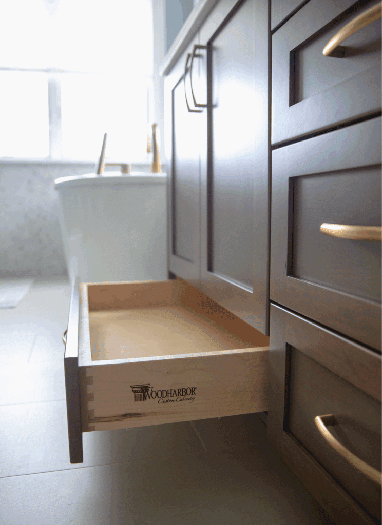 WoodHarbor Custom Cabinetry dovetail drawer construction with champagne bronze hardware in cherry Cashmere finish bathroom vanity