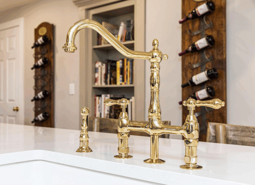 Gold bridge-style kitchen faucet on distressed walnut island with Calacatta Gold Silestone countertop in Belle Maison French-inspired luxury kitchen by KRB Kitchen + Bath Design Center