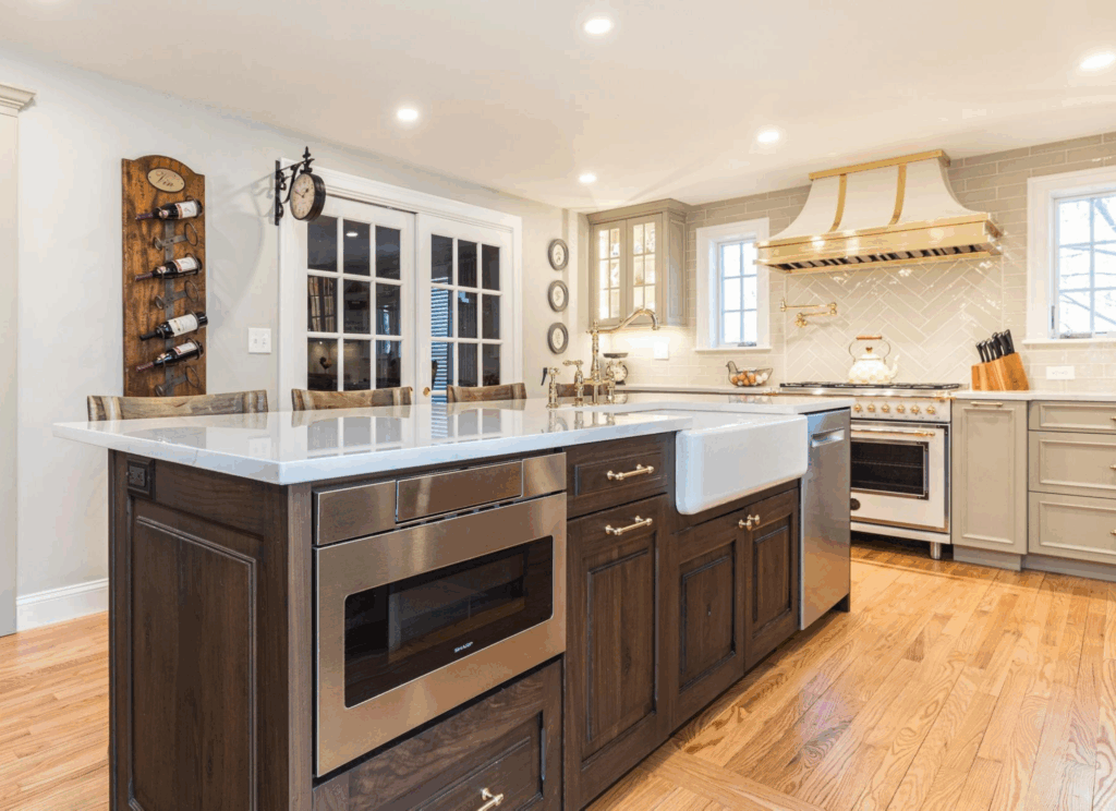 Belle Maison French-inspired luxury kitchen renovation featuring distressed walnut island, gray cabinetry, crystal chandelier, and round dining table in Seacoast New Hampshire home
