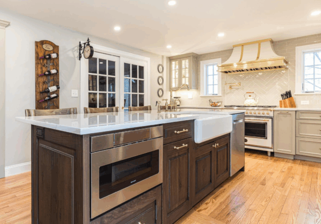Belle Maison French-inspired luxury kitchen renovation featuring distressed walnut island, gray cabinetry, crystal chandelier, and round dining table in Seacoast New Hampshire home