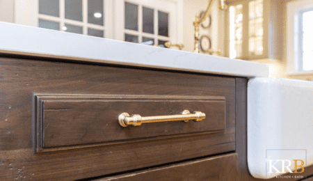Close up gold hardware on dark wood cabinets