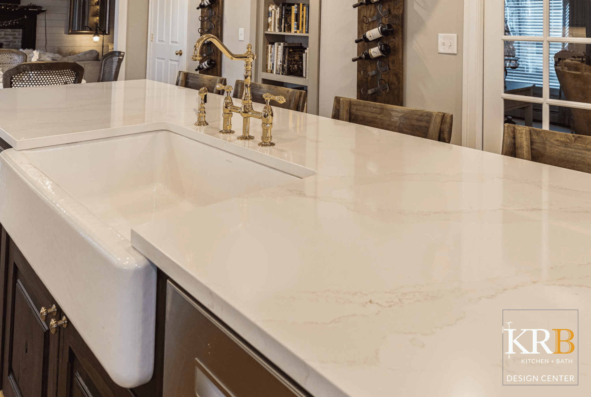 Close up of white marble countertops with farmhouse white sink and gold faucet