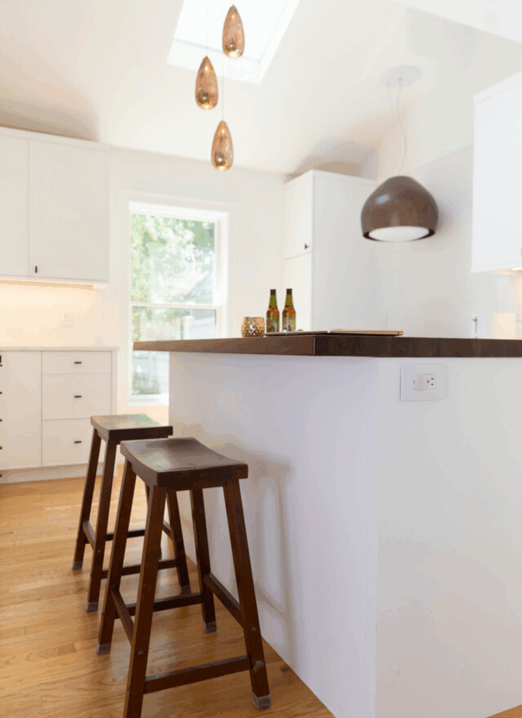 Custom Grothouse walnut wood countertop on white kitchen island with copper pendant lighting