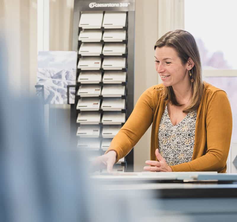 Smiling female interior designer pointing at design samples on a table at a kitchen and bath showroom