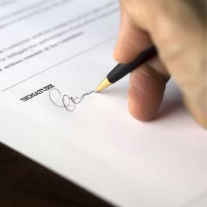 Close up of hand signing paperwork